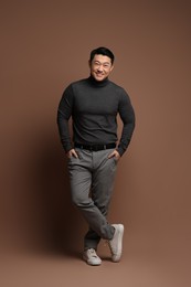 Full length portrait of happy man on brown background