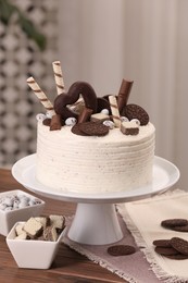 Delicious cake decorated with sweets on wooden table in kitchen