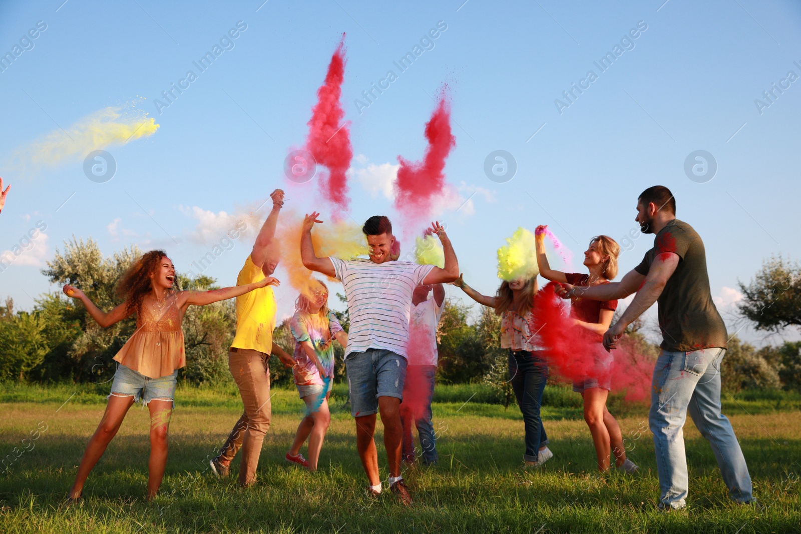 Photo of Happy friends having fun with colorful powder dyes outdoors. Holi festival celebration