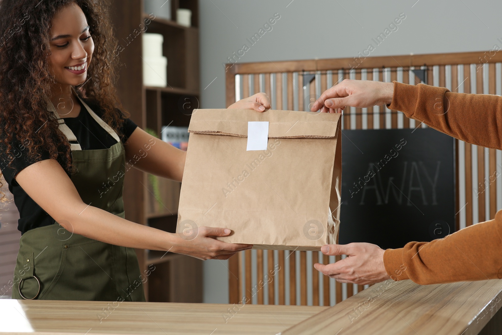 Photo of Worker giving paper bag to customer in cafe