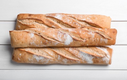 Photo of Tasty baguettes on white wooden table, flat lay