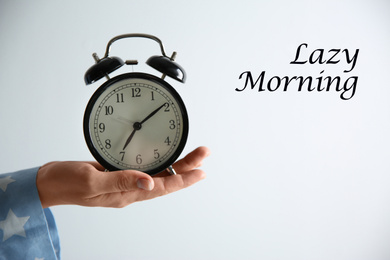 Image of Woman holding alarm clock on white background, closeup. Lazy morning