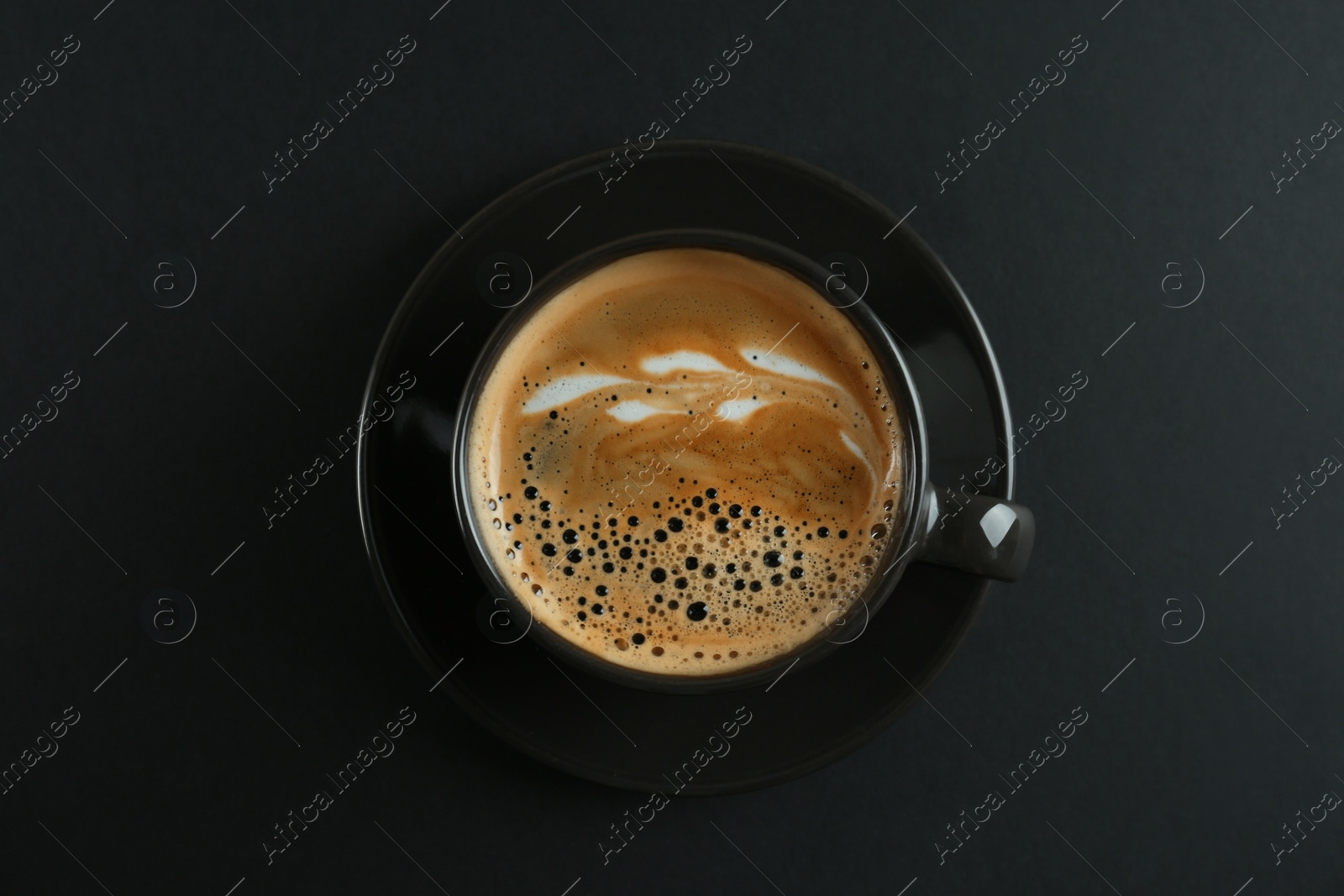 Photo of Cup of tasty coffee on black background, top view