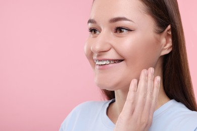 Photo of Smiling woman with dental braces on pink background. Space for text
