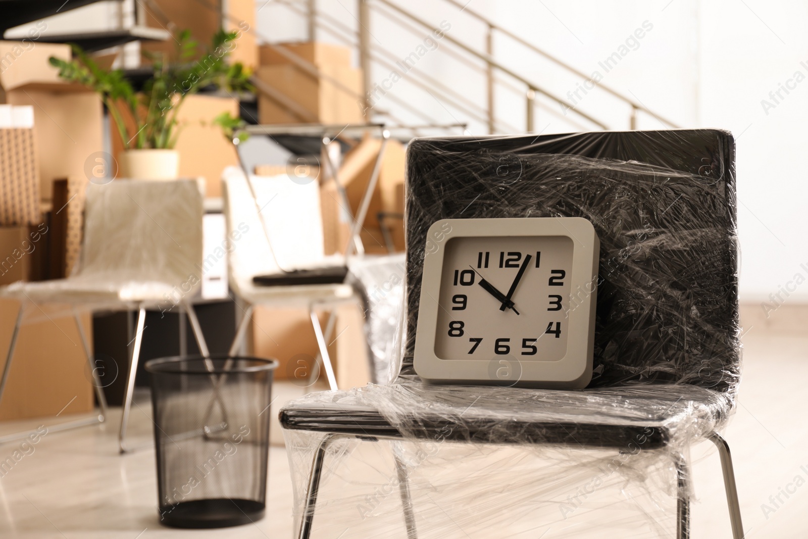 Photo of Packed chair and clock in office. Moving day