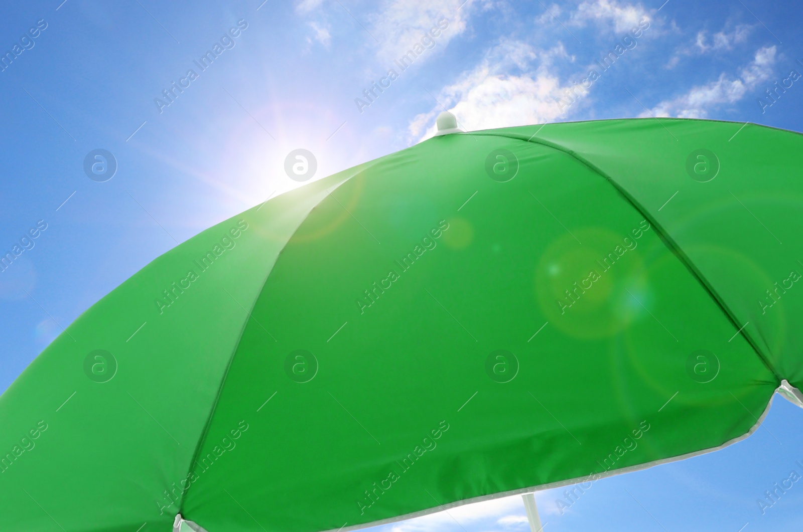 Image of Open big green beach umbrella and beautiful blue sky with white clouds on background