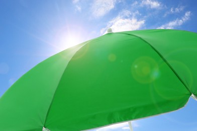 Image of Open big green beach umbrella and beautiful blue sky with white clouds on background