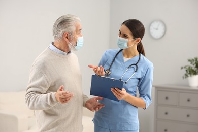 Photo of Nurse with clipboard consulting elderly patient in hospital