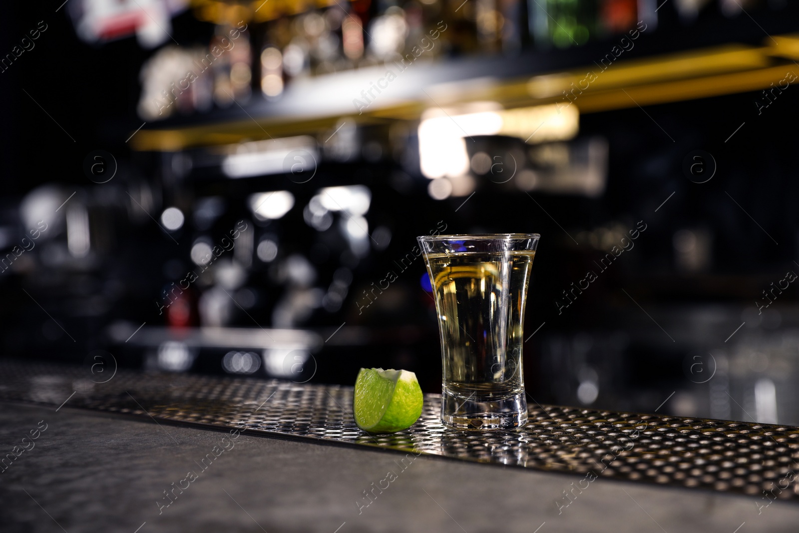 Photo of Mexican Tequila shot with lime slice on bar counter. Space for text