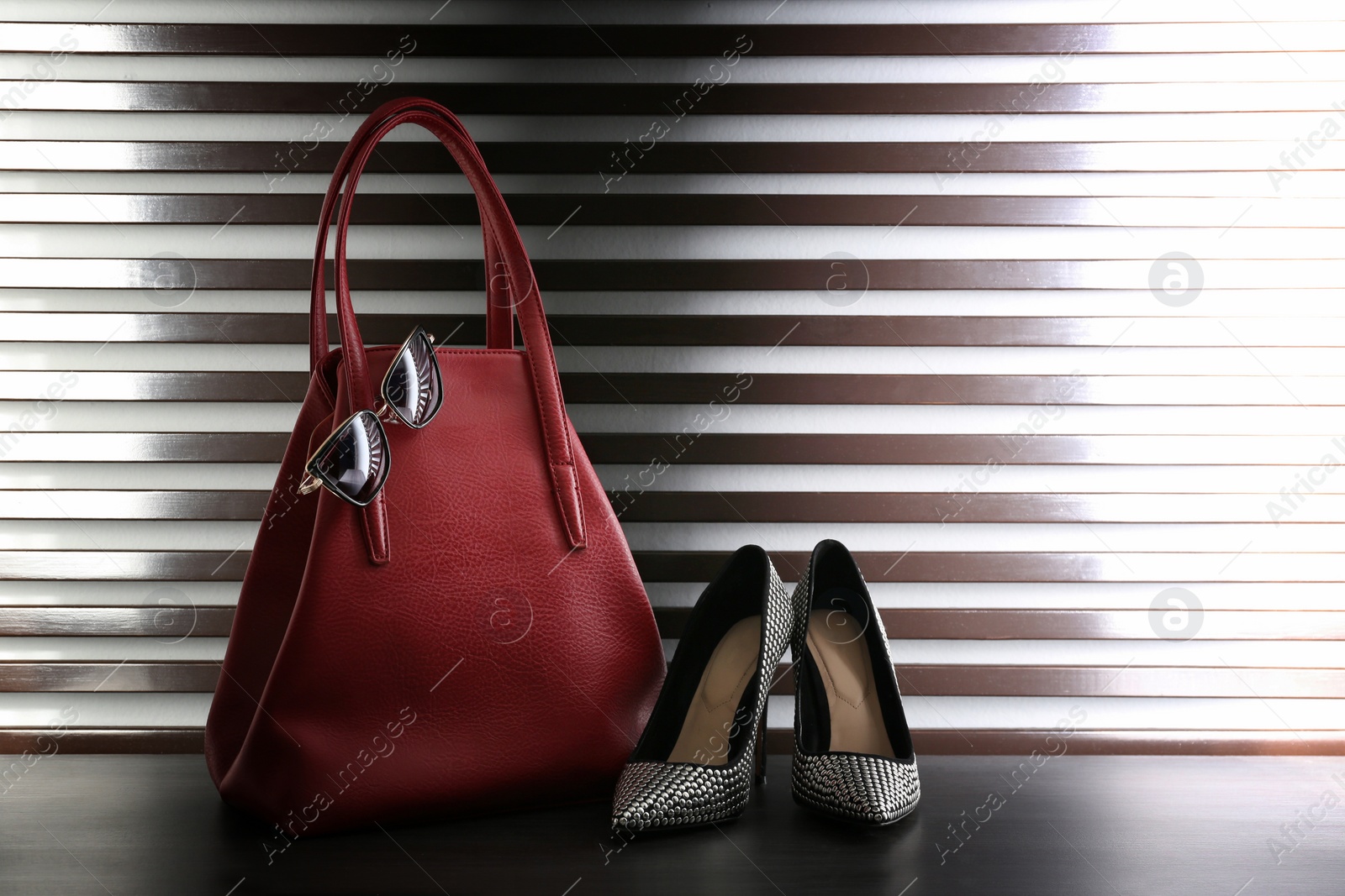 Photo of Stylish woman's bag, shoes and sunglasses on dark grey table