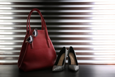 Photo of Stylish woman's bag, shoes and sunglasses on dark grey table