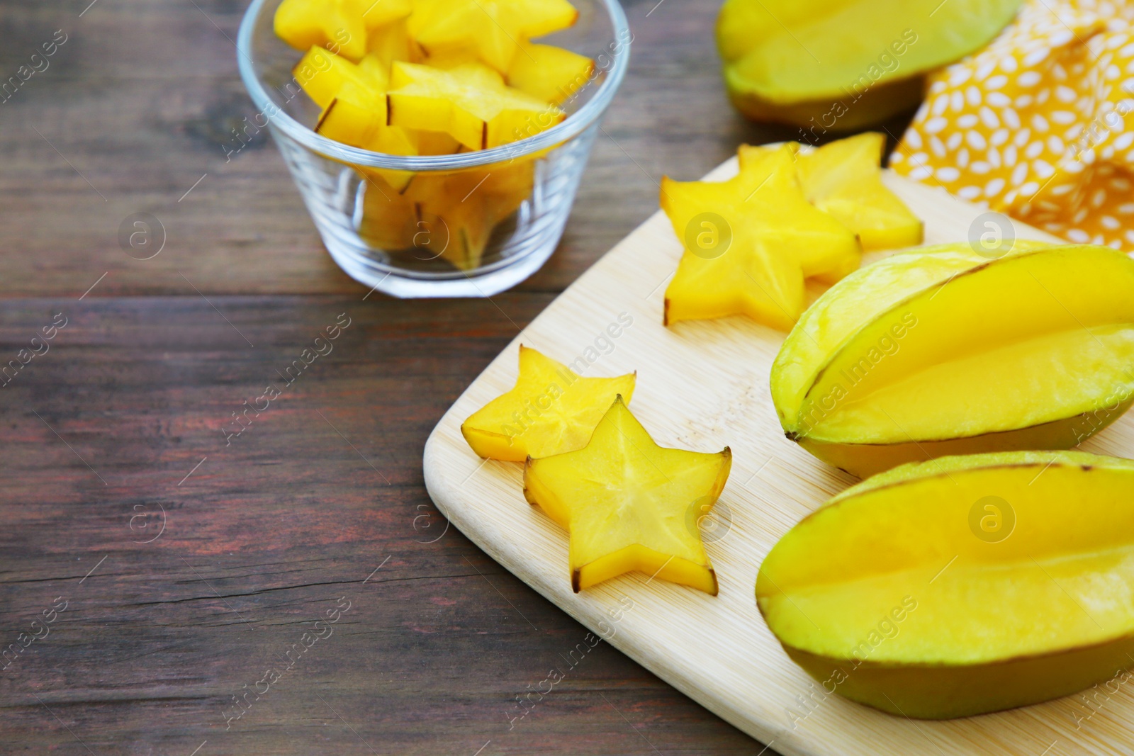 Photo of Delicious cut and whole carambolas on wooden table, space for text