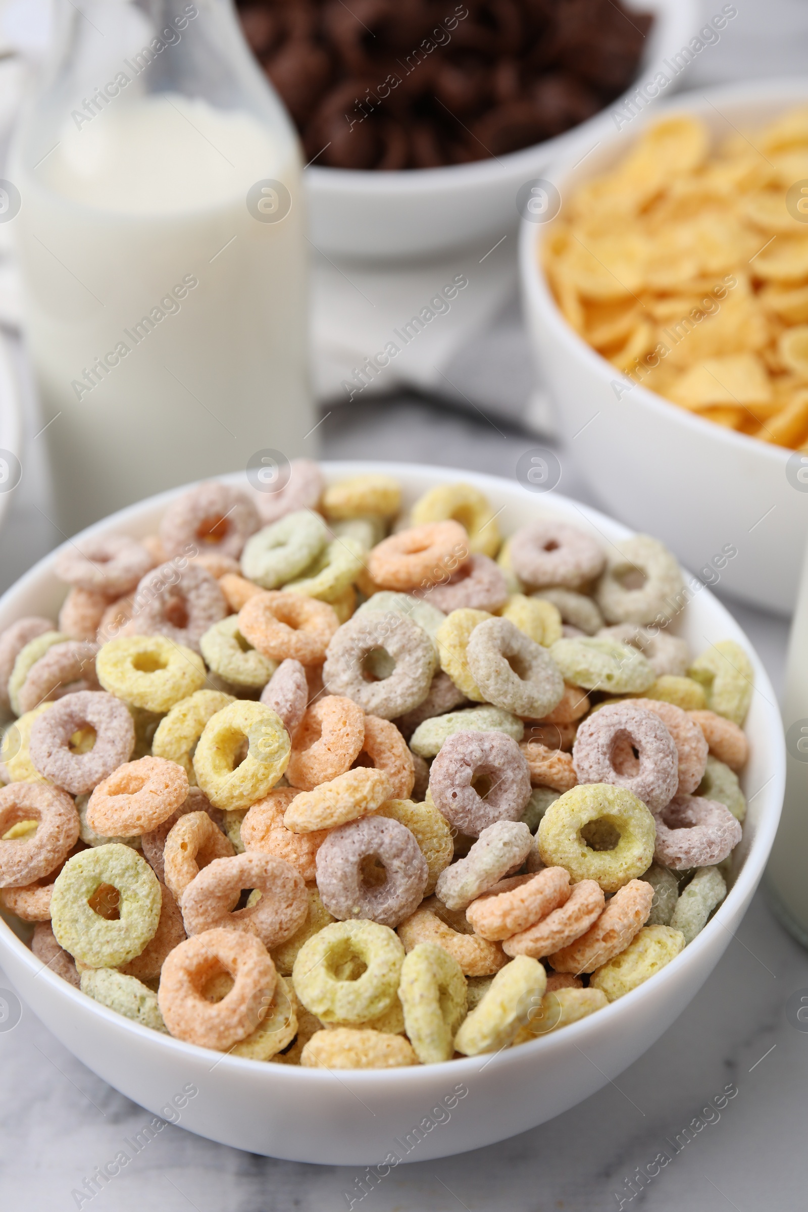 Photo of Different delicious breakfast cereals and milk on white marble table, closeup