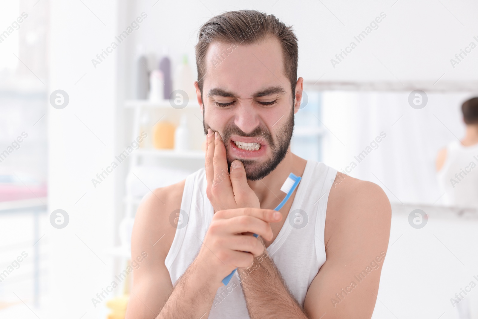 Photo of Young man suffering from toothache indoors