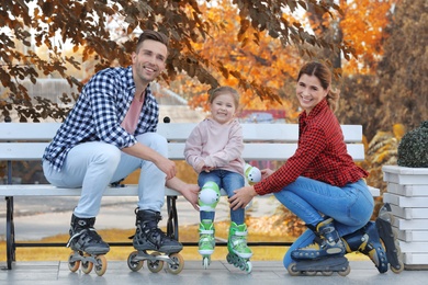 Photo of Happy family wearing roller skates on bench outdoors