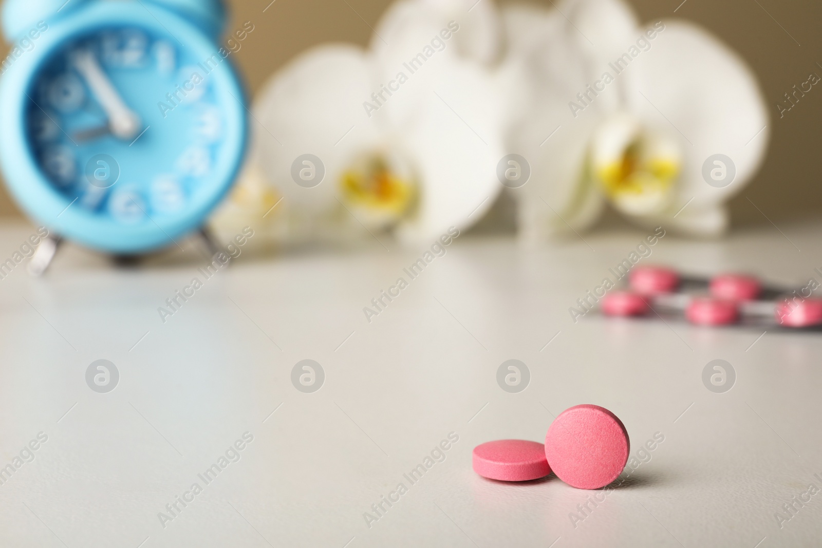 Photo of Pink pills on white table, space for text. Menopause concept