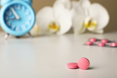 Photo of Pink pills on white table, space for text. Menopause concept