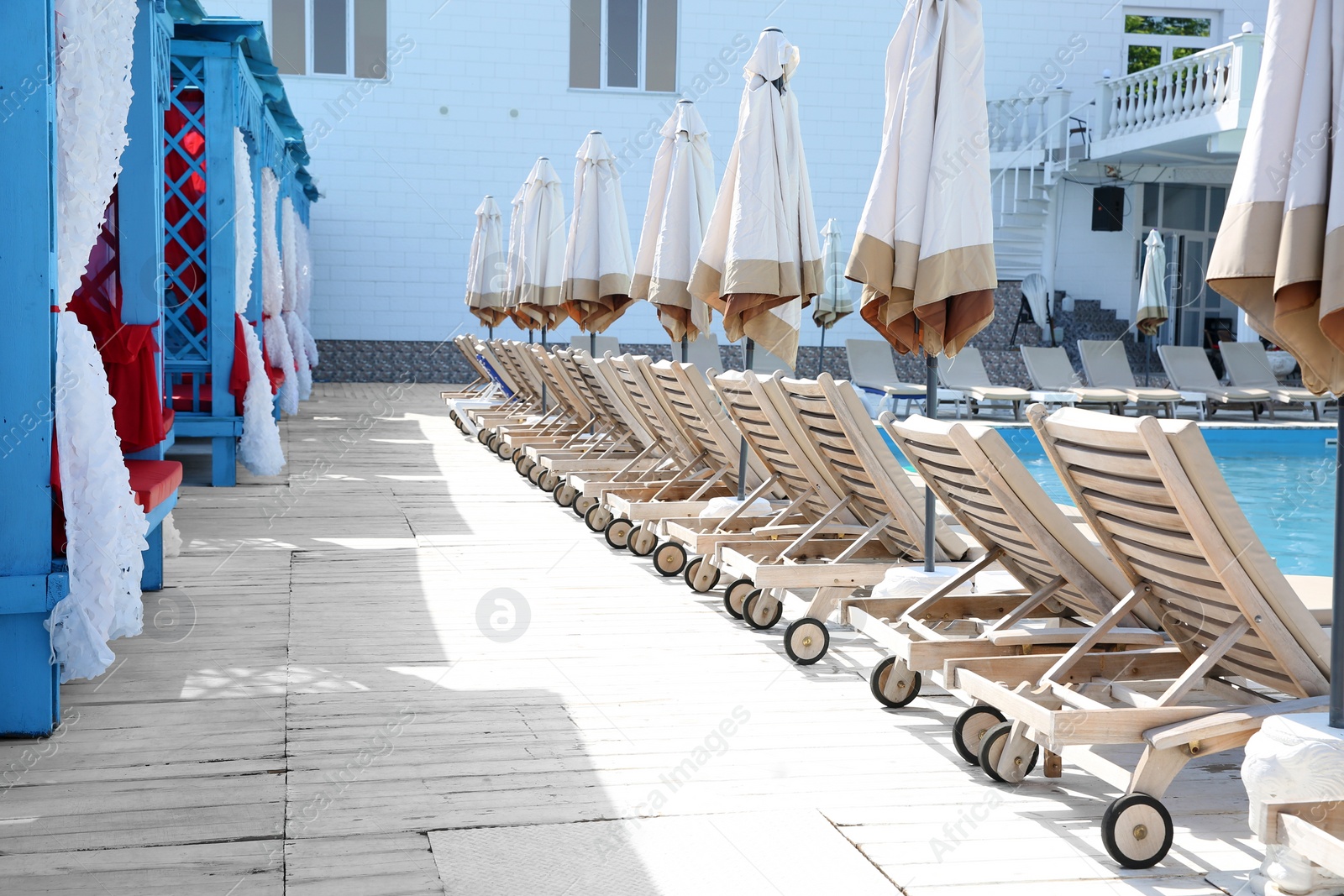 Photo of Comfortable sunbeds near outdoor swimming pool at resort on sunny day