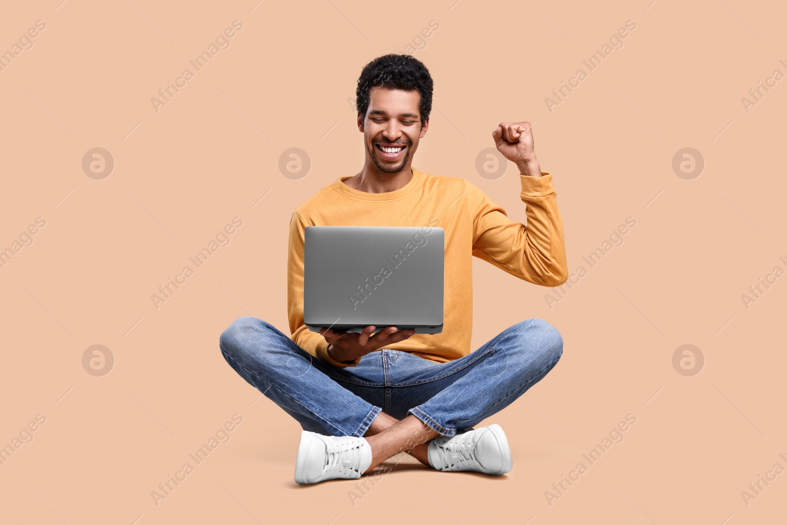 Photo of Happy man with laptop on beige background