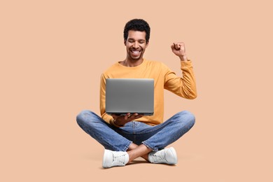 Photo of Happy man with laptop on beige background