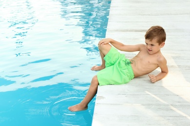 Photo of Little child near outdoor swimming pool. Dangerous situation