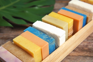 Many different handmade soap bars in wooden box on table, closeup