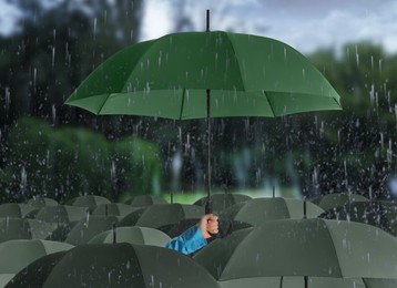 Image of Person holding umbrella over other under heavy rain outdoors 