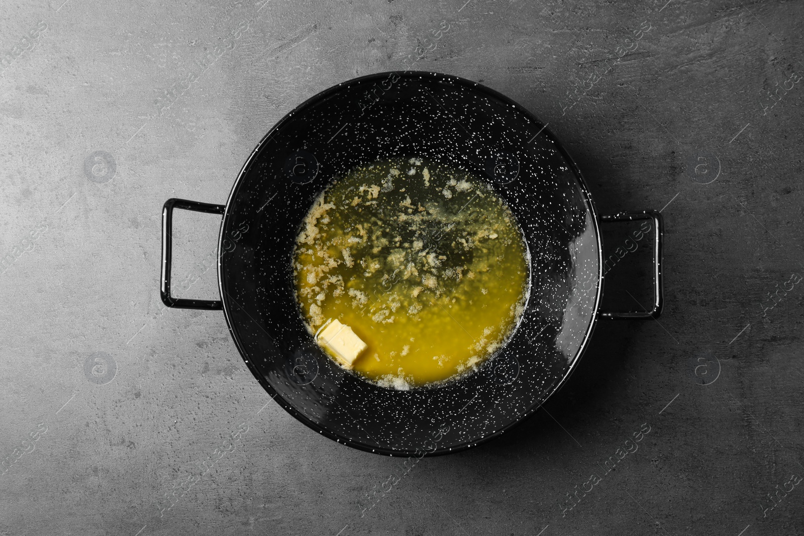 Photo of Frying pan with melting butter on grey table, top view