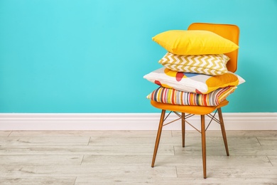 Photo of Different pillows on chair near color wall in room