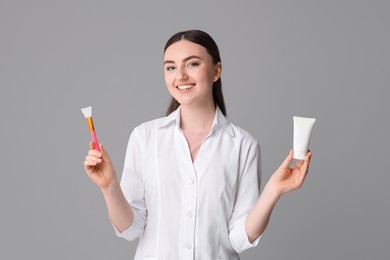 Cosmetologist with cosmetic product and silicone brush on grey background