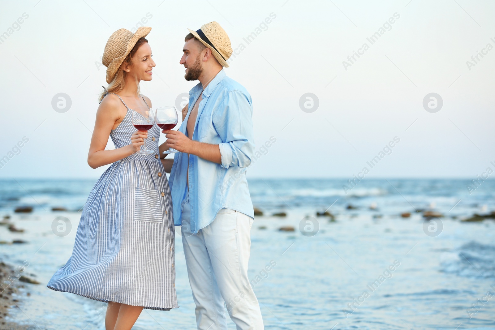 Photo of Young couple with glasses of wine on beach