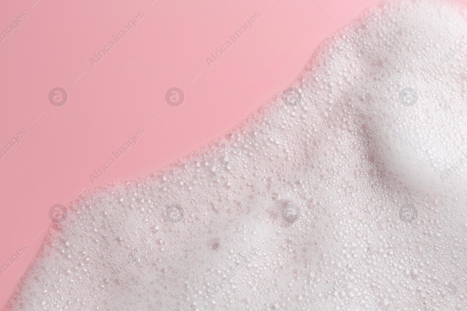 Photo of White fluffy foam on pink background, top view. Space for text