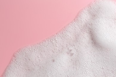 Photo of White fluffy foam on pink background, top view. Space for text