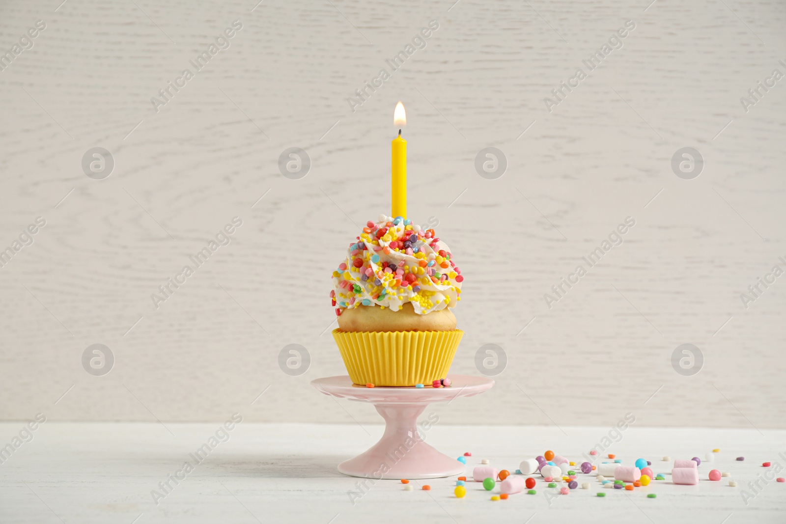 Photo of Birthday cupcake with candle on white table against wooden background