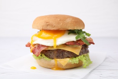 Delicious burger with fried egg on white table