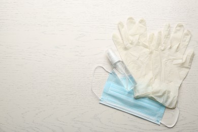 Photo of Medical gloves, protective mask and hand sanitizer on white wooden background, flat lay. Space for text
