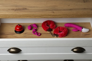Photo of Different modern sex toys in open wooden drawer