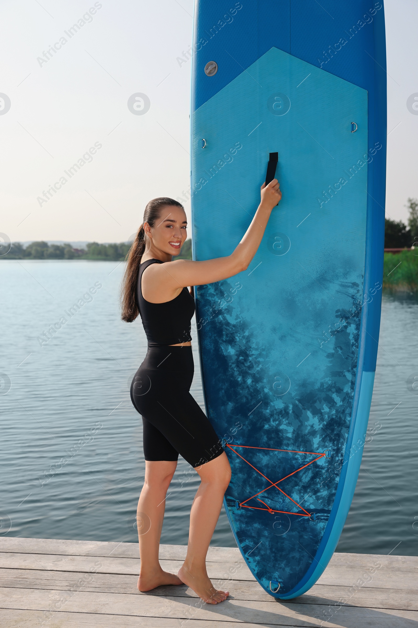 Photo of Woman standing near SUP board on pier