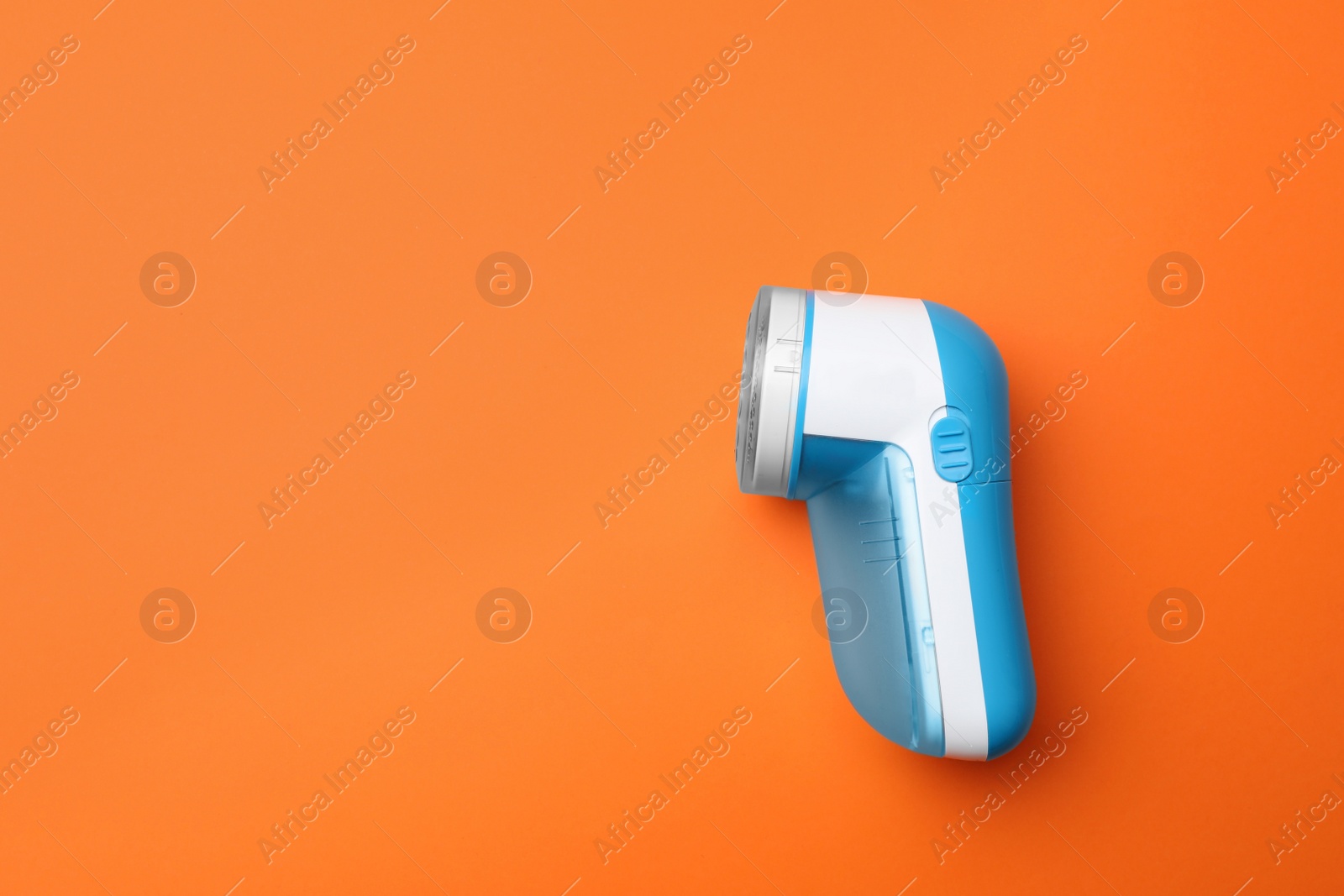 Photo of Modern fabric shaver on orange background, top view. Space for text