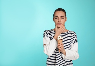 Photo of Emotional young woman with sensitive teeth and ice cream on color background. Space for text