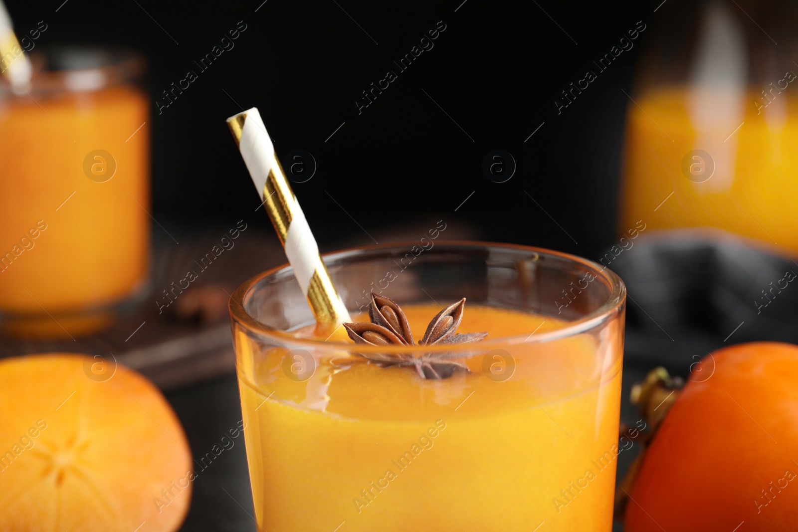 Photo of Tasty persimmon smoothie with anise and straw, closeup