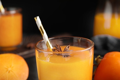 Photo of Tasty persimmon smoothie with anise and straw, closeup