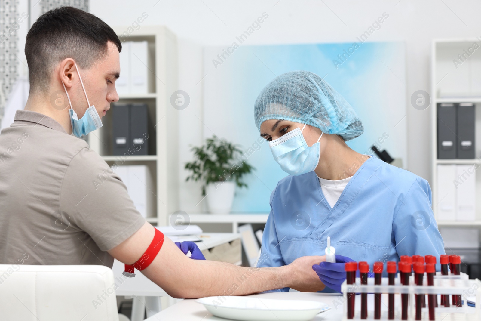 Photo of Laboratory testing. Doctor taking blood sample from patient at white table in hospital