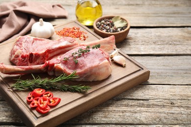Photo of Fresh tomahawk beef cuts and spices on wooden table. Space for text
