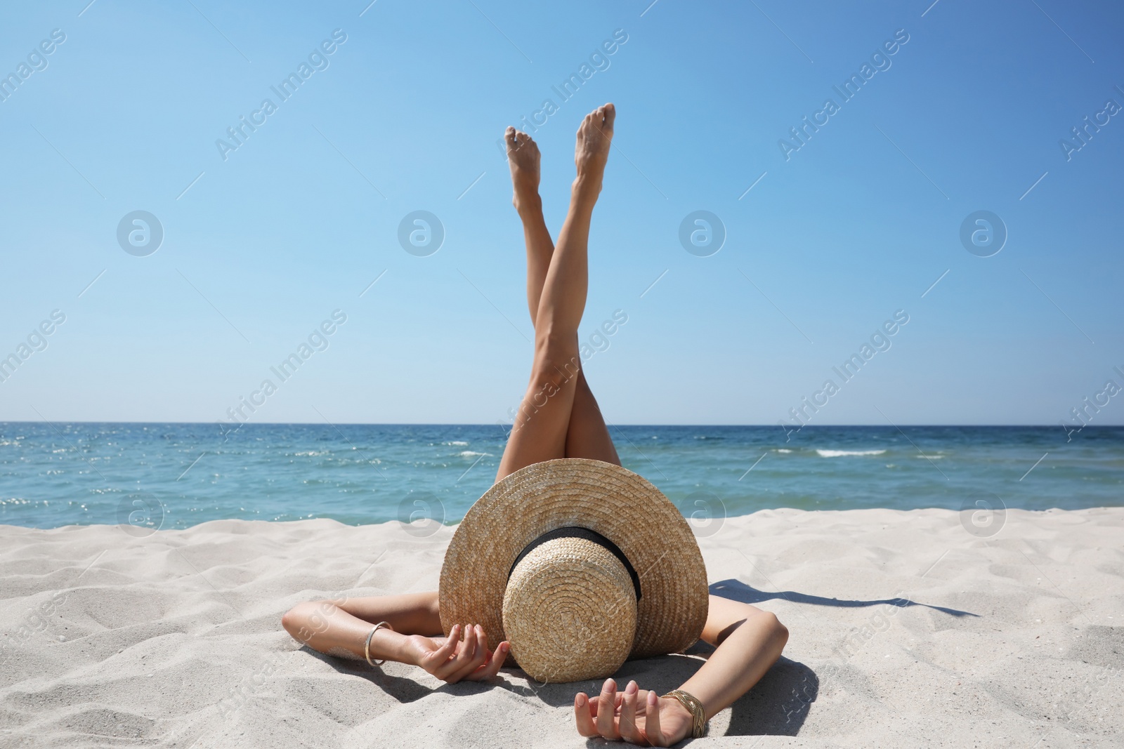 Photo of Woman with straw hat lying on sandy beach near sea 