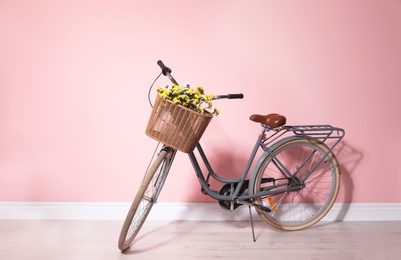 Retro bicycle with wicker basket near color wall