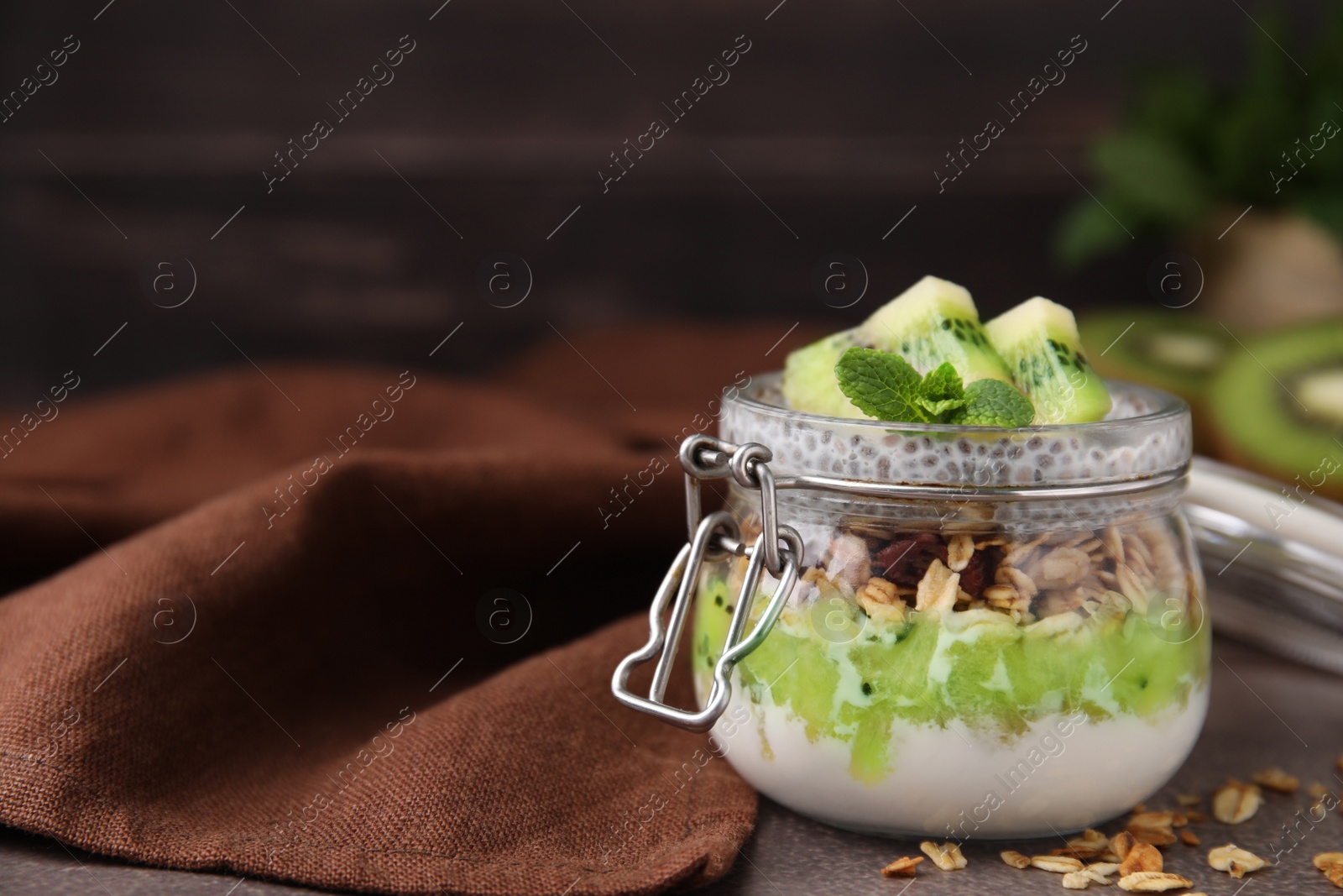 Photo of Delicious dessert with kiwi and chia seeds on brown table, closeup. Space for text