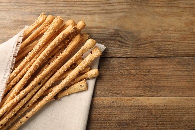 Delicious grissini sticks with napkin on wooden table, top view. Space for text