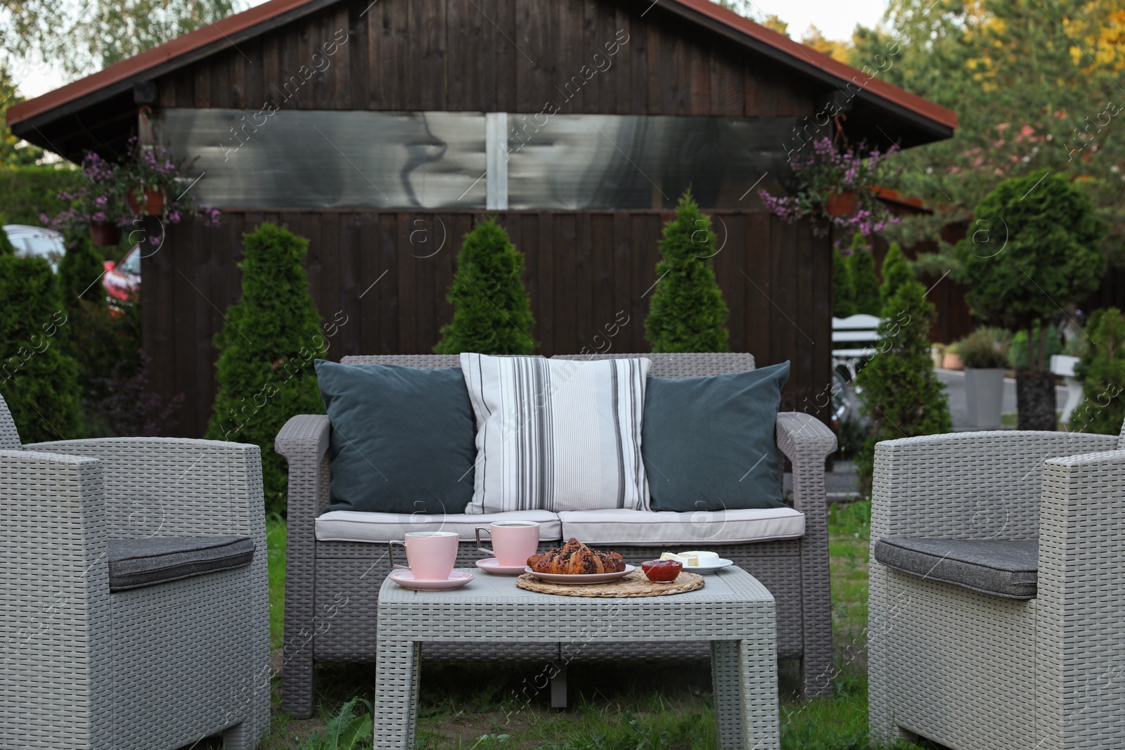 Outdoor breakfast with tea and croissants on rattan table in garden Photo of Outdoor breakfast with tea and croissants on rattan table in garden
