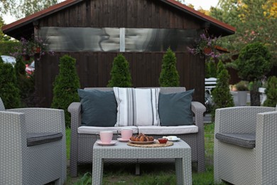 Photo of Outdoor breakfast with tea and croissants on rattan table in garden